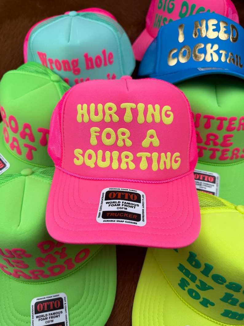 May include: A collection of trucker hats in various neon colors, including pink, green, and blue. Each hat features bold, humorous text in a contrasting color. The hats have a mesh back and a snap closure.