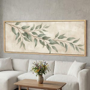 Può includere: Un'opera d'arte murale rettangolare orizzontale raffigurante un ramo dipinto con foglie verde salvia su uno sfondo color crema strutturato, racchiusa in una cornice di legno chiaro. L'opera presenta un motivo botanico con foglie allungate.