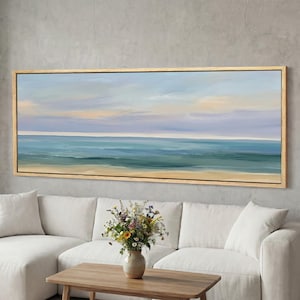 Könnte beinhalten: Ein Ölgemälde einer Meereslandschaft mit hellblauem Himmel und Ozean. Das Kunstwerk ist in einem Naturholzrahmen gerahmt und hängt über einem weißen Sofa. Der Ozean geht von Türkis zu einem Sandstrand über.