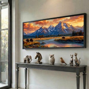 May include: A landscape painting of mountains and a river with a sunset sky, framed in black, hangs above a dark gray console table. The table displays decorative animal figurines, including an elephant, horse head, owl, bird, and two cats.