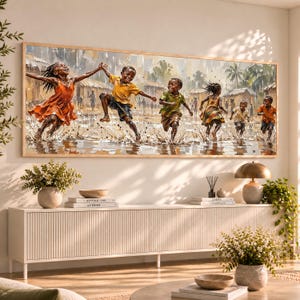 Op de afbeelding: Een rechthoekige ingelijste wandkunstprint met een groep kinderen die in ondiep water spelen tijdens een regenbui. De kinderen dragen kleurrijke kleding en zijn in beweging vastgelegd terwijl ze spetteren en door het water rennen.
