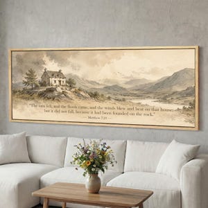 May include: A framed landscape print featuring a watercolor painting of a house on a hill, mountains, and a lake. The artwork has a sepia tone and includes the text "The rain fell...founded on the rock." - Matthew 7:25.
