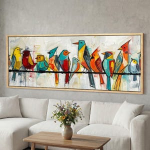 Puede incluir: Una obra de arte en lienzo enmarcada que presenta una fila de coloridas aves posadas en un alambre negro. Las aves están pintadas en tonos vibrantes de amarillo, rojo, azul y naranja sobre un fondo blanco texturizado. La obra de arte está encerrada en un marco de madera natural.