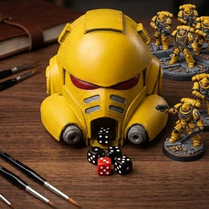 May include: A yellow helmet-shaped dice box with red eye details, holding black and red dice. Miniature yellow figures with weapons stand nearby. Paintbrushes and a notebook are in the background. A tabletop game theme.