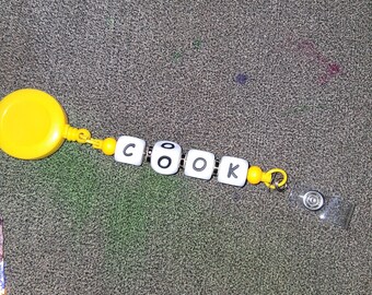 Badgehaspel met 'COOK'-letterkralen – gele sluiting, meerdere kleuren