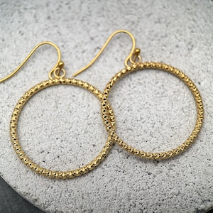 May include: A white ceramic mug with a black handle and the text "But First, Coffee" in a bold, black font. The mug is set against a neutral background, highlighting its simple design.