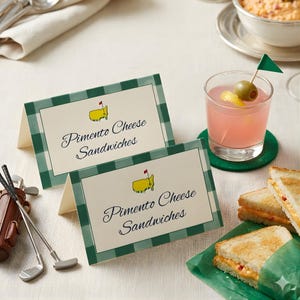 May include: Two folded place cards with green gingham borders and the text "Pimento Cheese Sandwiches" are displayed. A golf-themed logo is at the top. A cocktail with an olive and a sandwich are also visible.