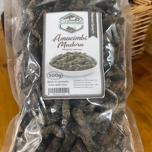 May include: A white ceramic mug with a black handle and the text "But First, Coffee" in a black, handwritten-style font. The mug is on a white surface.