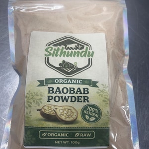 Puede incluir: Bolsa transparente con polvo de baobab. La etiqueta muestra "Sithundu" sobre "Organic Baobab Powder" y una ilustración de fruta de baobab. La etiqueta también indica "100% Natural" y "Net Wt. 100g."