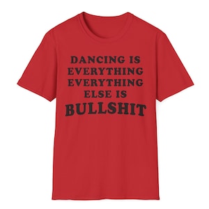 May include: A red short-sleeved t-shirt featuring black text printed on the front that reads: DANCING IS EVERYTHING EVERYTHING ELSE IS BULLSHIT. The garment has a crew neckline and a standard fit, showcasing bold typography against the solid red fabric.