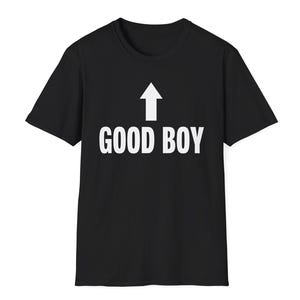 Op de afbeelding: Een zwart t-shirt met korte mouwen voorzien van een witte pijl die naar boven wijst, met daaronder de tekst GOOD BOY gedrukt in een vet, schreefloos lettertype in het midden op de borst van het kledingstuk.
