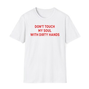 May include: A white short-sleeved t-shirt featuring the red text DON'T TOUCH MY SOUL WITH DIRTY HANDS printed in the center of the chest. The garment has a crew neckline and a standard fit, showcasing a clean design with bold red lettering.