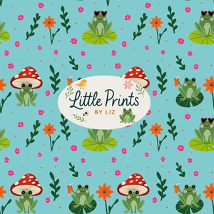 Peut inclure: Motif répétitif sur fond bleu clair avec des grenouilles, des champignons, des fleurs et des feuilles de dessin animé. Les grenouilles portent des lunettes de soleil et sont assises sur des nénuphars. Le texte "Little Prints by Liz" est dans un ovale blanc.