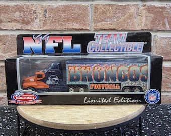 May include: A Denver Broncos NFL Team Collectible semi-truck toy in its original packaging. The truck features an orange cab with the number 99 and a blue trailer with holographic lettering. The box displays the NFL logo and Limited Edition text.