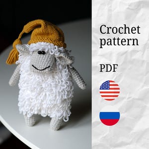 May include: A handmade crochet sheep wearing a mustard yellow nightcap. The sheep has a white, fluffy body, gray face, arms, and legs. The image includes the text "Crochet pattern PDF" and the American flag.