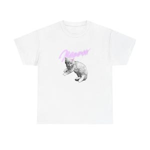 以下が含まれることがあります： ピンクのリボンをつけた猫のグレースケール画像と、筆記体で「meow」という文字が入った白いTシャツ。猫は遊び心のあるポーズをしています。シャツは柔らかい素材で作られています。