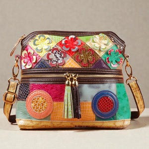 May include: A vibrant patchwork crossbody bag with floral and geometric patterns. The bag showcases a mix of textures and colours, including red, green, blue, and yellow. It has a zip closure, a shoulder strap, and decorative tassels.