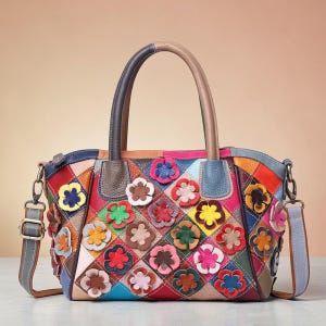 Op de afbeelding: Een kleurrijke patchwork leren handtas met een bloemenmotief. De tas heeft een verscheidenheid aan kleuren, waaronder rood, blauw, groen en geel, met een handvat aan de bovenkant en een afneembare schouderriem. De tas is versierd met 3D-bloemapplicaties.