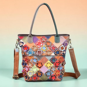 May include: A multi-coloured leather tote bag featuring a diamond-quilted pattern in various hues. The exterior is adorned with numerous three-dimensional leather flower appliqués in shades of red, blue, yellow, orange, and purple. It has two top handles and a detachable brown shoulder strap.