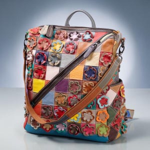 May include: A multi-colored leather backpack featuring a patchwork design of square panels in various hues including yellow, red, blue, and purple. The exterior is decorated with numerous three-dimensional leather flower appliqués.