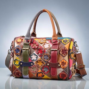 Può includere: Una borsa in pelle multicolore caratterizzata da un motivo a rombi patchwork con applicazioni floreali tridimensionali. La borsa include due manici superiori, due cinghie verticali con fibbia sul davanti e una tracolla rimovibile in metallo.