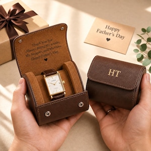 May include: A rectangular Citizen wristwatch with a white face and gold-tone case, housed in a brown leather travel case. The interior lid is engraved with "Thank You For Always Being My Guide, My Support, and My Hero. Happy Father's Day." The exterior is monogrammed "HT".