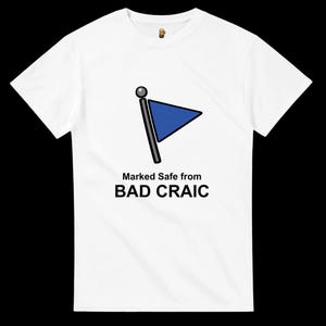 Puede incluir: Camiseta blanca con un gráfico de una bandera azul sobre un poste gris. El texto "Marked Safe from BAD CRAIC" está impreso debajo. La camiseta tiene cuello redondo y mangas cortas.