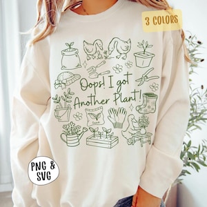 Könnte beinhalten: Cremefarbenes Sweatshirt mit einem grünen Gartenmotiv. Das Design umfasst Illustrationen von Gartengeräten, Pflanzen, Enten und den Text "Oops! I got Another Plant!". Oben rechts befindet sich ein gelbes Rechteck mit dem Text "3 COLORS". Unten links befindet sich ein schwarzer Kreis mit dem Text "PNG & SVG".