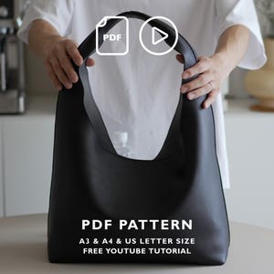 Peut inclure: Un sac à bandoulière noir de style hobo avec une surface texturée et une anse intégrée unique. L'image contient le texte blanc PDF PATTERN, A3 & A4 & US LETTER SIZE, et FREE YOUTUBE TUTORIAL, ainsi que des icônes PDF et de lecture.