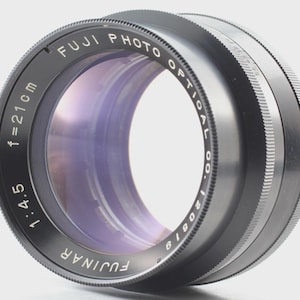 Op de afbeelding: Een zwarte Fujinar cameralens met de tekst "FUJI PHOTO OPTICAL CO." en "f=21cm". De lens heeft een diafragma van 1:4.5 en een geribbelde focusring. De lens heeft een paars en blauw interieur.