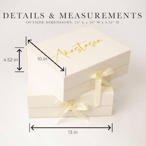 May include: A cream-coloured rectangular gift box with a gold script name Anastasia on the lid and a satin ribbon closure. The box measures 33.02 cm long, 25.4 cm wide, and 11.48 cm high, as indicated by the text and dimension lines.