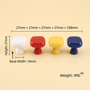 May include: Four square cabinet knobs in white, red, yellow, and blue. Each knob has a height of 27mm and a base width of 14mm. The total width of the four knobs is 108mm. The set of four knobs has a combined weight of 49g. The knobs are glossy.