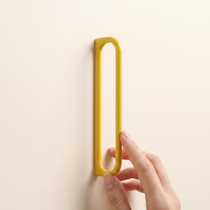 May include: A bright yellow, elongated, oval-shaped metal handle or pull with a smooth, matte finish. The object features a continuous, rounded frame design with an open center, providing a sleek and functional grip for cabinets or drawers.