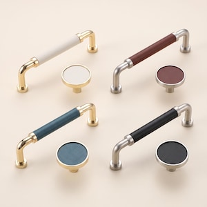 May include: Four sets of cabinet hardware, each including a long bar handle and a round knob. The hardware features metallic finishes in gold and silver tones, paired with cylindrical and circular inserts in white, brown, blue, and black colors.