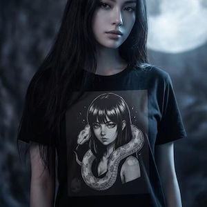 Può includere: T-shirt nero con grafica in bianco e nero di una donna con un serpente intorno al collo. Il serpente è dettagliato. La maglietta è a girocollo e maniche corte.