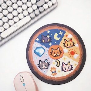 K&ouml;nnte beinhalten: Rundes Mauspad mit Pixel-Art-Katzenmotiven in einem segmentierten Muster. Das Pad ist von einem braunen Rand umgeben und enth&auml;lt eine hellrosa Maus und eine wei&szlig;e und graue Tastatur. Der Text "@ Qi Qi Plaza" ist sichtbar.