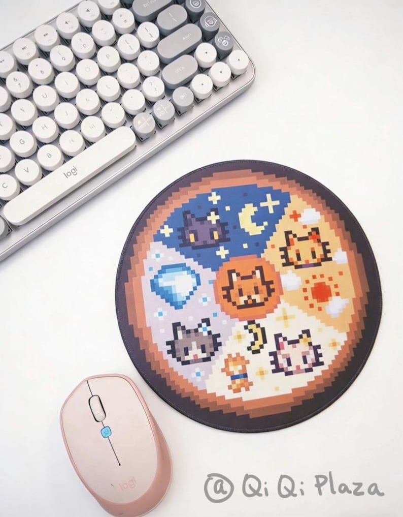 K&ouml;nnte beinhalten: Rundes Mauspad mit Pixel-Art-Katzenmotiven in einem segmentierten Muster. Das Pad ist von einem braunen Rand umgeben und enth&auml;lt eine hellrosa Maus und eine wei&szlig;e und graue Tastatur. Der Text "@ Qi Qi Plaza" ist sichtbar.