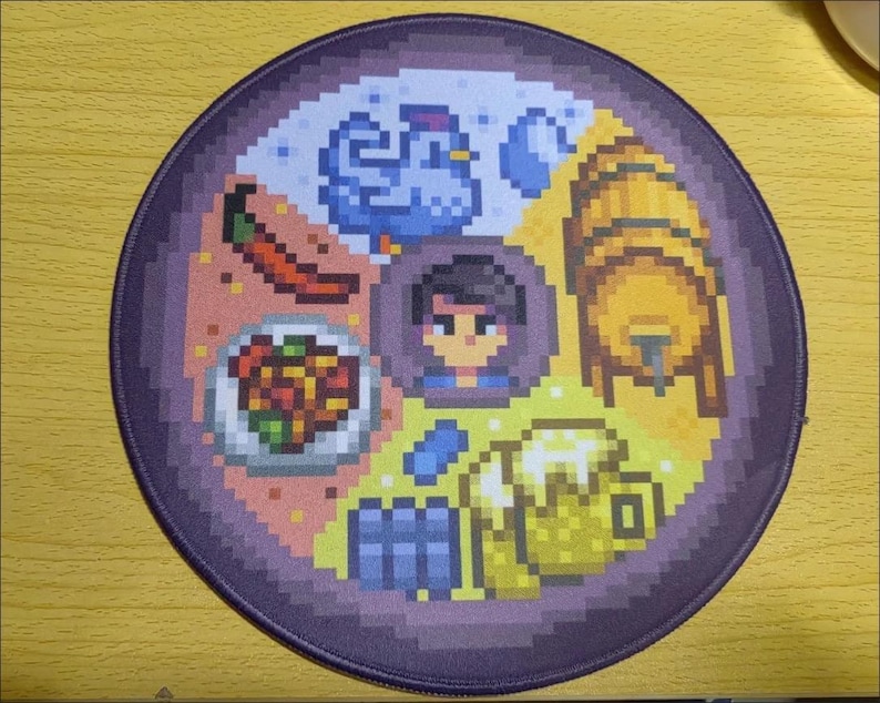 K&ouml;nnte beinhalten: Rundes Mauspad mit lila Rand und Pixelkunst-Design. Es zeigt eine zentrale Figur, umgeben von pixeligen Bildern eines Huhns, einer Chili, Essen, einem Fass, Bier und anderen Elementen. Die Farbpalette umfasst Blau-, Gelb- und Rott&ouml;ne.