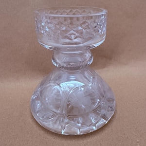 May include: A white ceramic mug with a black handle and the text "But First, Coffee" in a black, handwritten-style font. The mug is on a white surface.