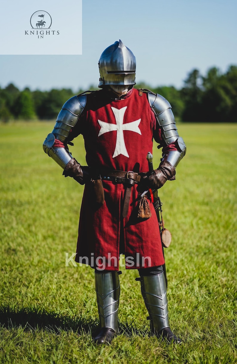 May include: A full suit of medieval armor, including a helmet, chest plate, and leg guards. The red tunic features a white cross. The image includes the text "Knights In". The knight stands in a grassy field.