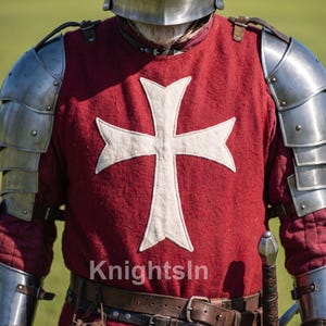 May include: A medieval knight's outfit, featuring a red tunic with a white cross emblem, metal armor, and a helmet. The image includes a sword and leather belt. The text "Knights In" is visible.
