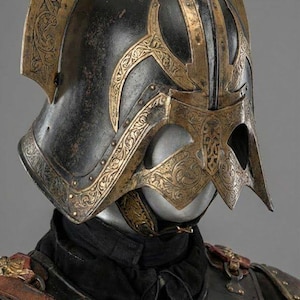 May include: A close-up of a medieval helmet with intricate gold-colored filigree designs on a black base. The helmet has a visor and a crest, and is part of a suit of armor. The Knights In logo is visible in the upper left corner.