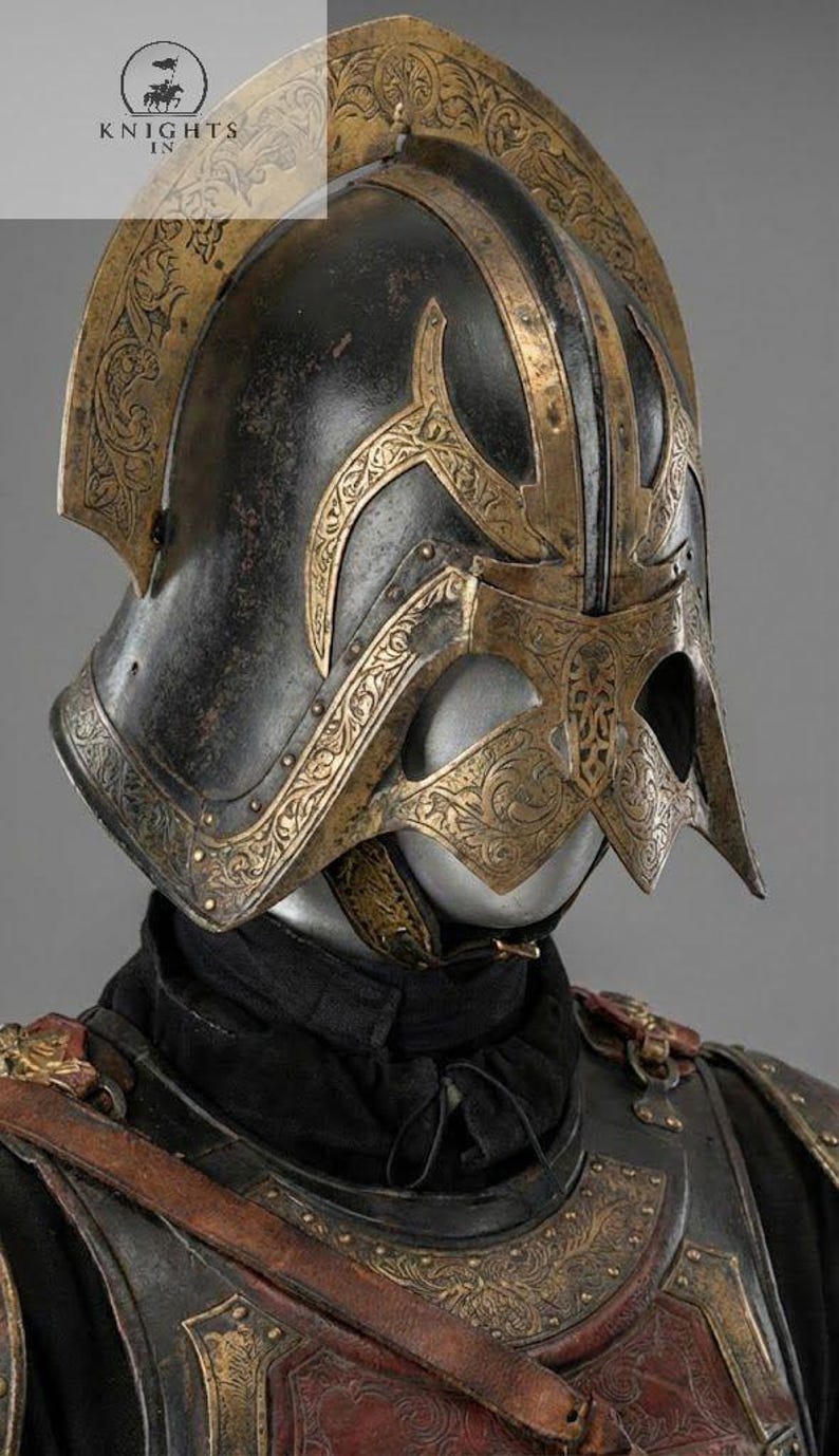 May include: A close-up of a medieval helmet with intricate gold-colored filigree designs on a black base. The helmet has a visor and a crest, and is part of a suit of armor. The Knights In logo is visible in the upper left corner.