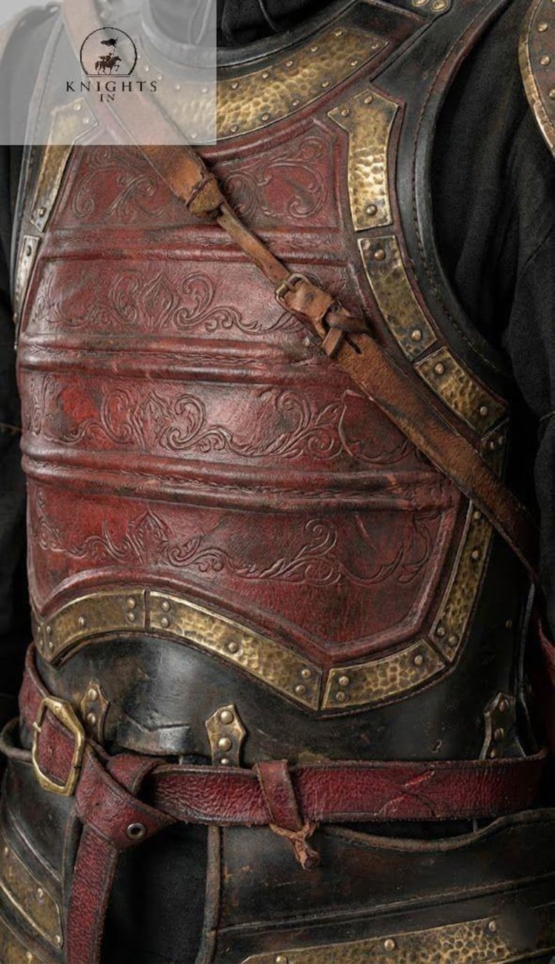 May include: Close-up of a medieval-style leather breastplate with intricate embossed designs. The armor features a deep red central panel, accented with brass-colored metal trim and straps. The text "KNIGHTS IN" is visible in the upper left corner.