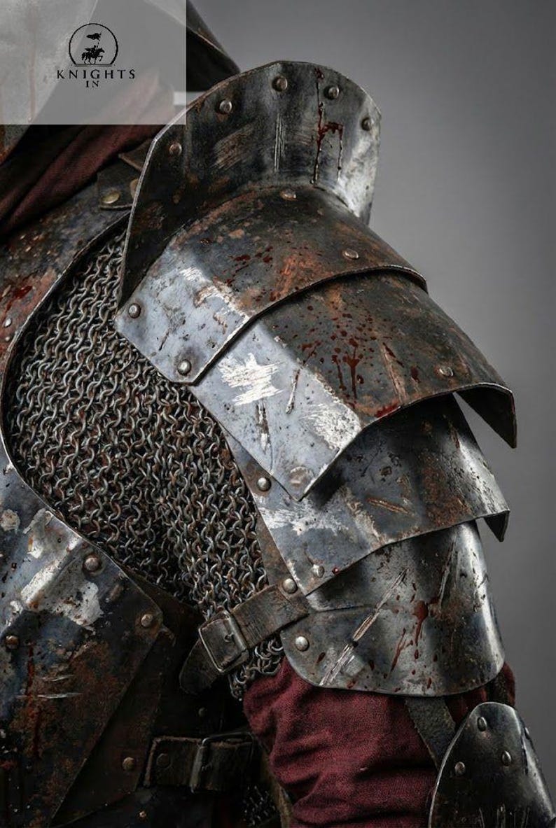 May include: Close-up of medieval armor, featuring layered steel plates and chainmail. The armor has a weathered, battle-worn appearance with visible blood spatter. A leather strap with a buckle is also visible. The image includes the text "KNIGHTS IN".