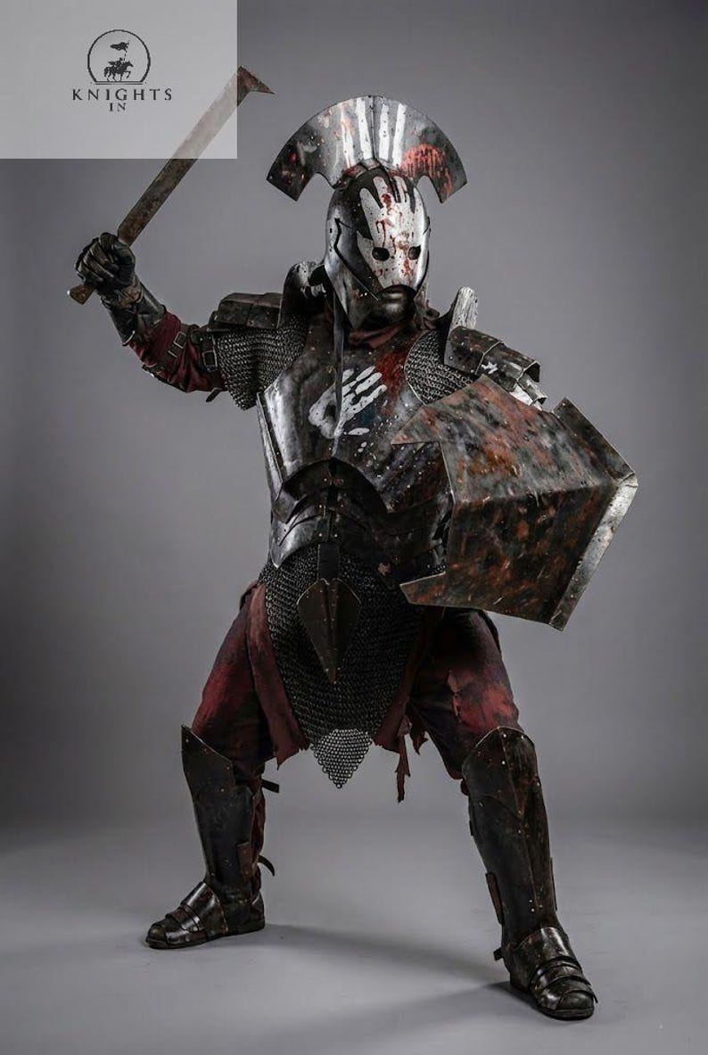May include: A warrior in full armor, wielding a battle axe and shield. The costume features a helmet with a handprint design, chainmail, and distressed metal plating. The image includes the text "Knights In".