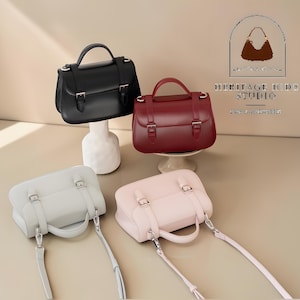 Vintage genuine leather crossbody handbag with retro Cambridge satchel design displayed in elegant neutral studio setting. Women’s minimalist shoulder purse available in black, burgundy red, ivory white, and blush pink colors with structured silhouette, buckle strap details, top handle, and adjustable crossbody strap. Japanese style leather handbag styled for modern fashion lovers, classic British satchel aesthetic, everyday women’s purse, elegant casual shoulder bag.