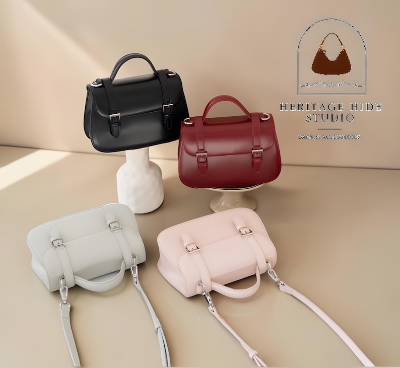 Vintage genuine leather crossbody handbag with retro Cambridge satchel design displayed in elegant neutral studio setting. Women’s minimalist shoulder purse available in black, burgundy red, ivory white, and blush pink colors with structured silhouette, buckle strap details, top handle, and adjustable crossbody strap. Japanese style leather handbag styled for modern fashion lovers, classic British satchel aesthetic, everyday women’s purse, elegant casual shoulder bag.