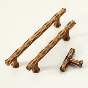 May include: Four bronze-colored cabinet pulls and knobs. Two long pulls, one short pull, and one knob. The hardware has a textured, hammered appearance. The pulls are approximately 8 inches long, and the knob is about 2 inches long.