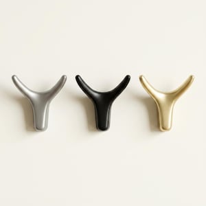 Puede incluir: Tres perchas de pared decorativas en plata, negro y dorado. Cada gancho tiene un diseño en forma de Y con bordes redondeados. Los ganchos están montados sobre una superficie blanca, mostrando su estética minimalista y variaciones de color.